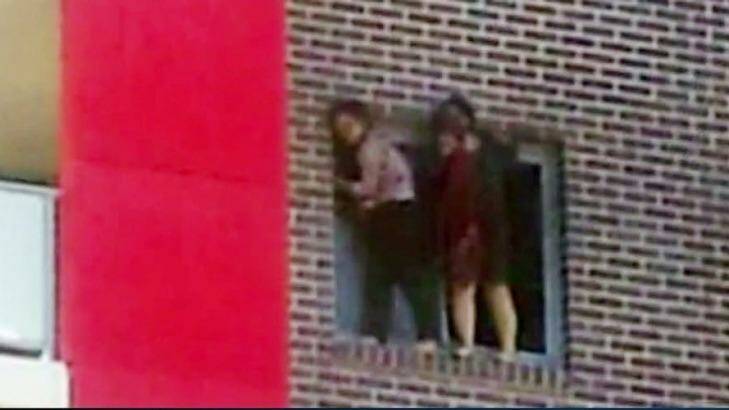 Connie Zhang and Yinuo Jiang hang on to the window of their Bankstown flat before jumping to escape the fire. Photo: ABC News 24