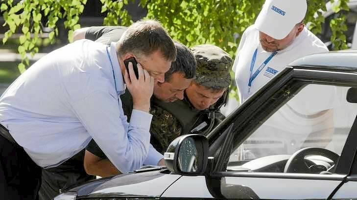 Alexander Hug, deputy head of the OSCE mission to Ukraine, left, his colleagues and a pro-Russian rebel, second right, examine a map as they try to estimate security conditions around the site of the crashed Malaysia Airlines Flight 17. Photo: Dmitry Lovetsky