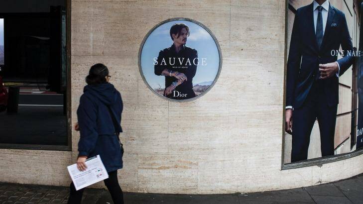 Commuters walk past the Dior Sauvage advertisement featuring Johnny Depp outside David Jones' Sydney CBD store. Photo: Dominic Lorrimer