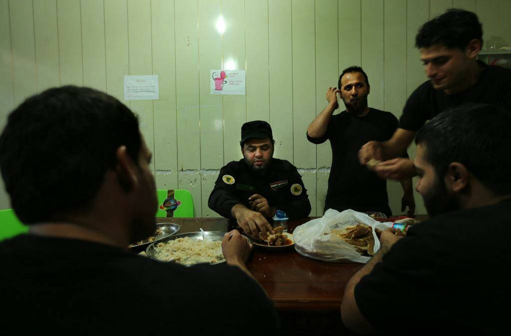 'We have a creed': Imam Ali Brigade fighters take their evening meal together. Photo: Kate Geraghty