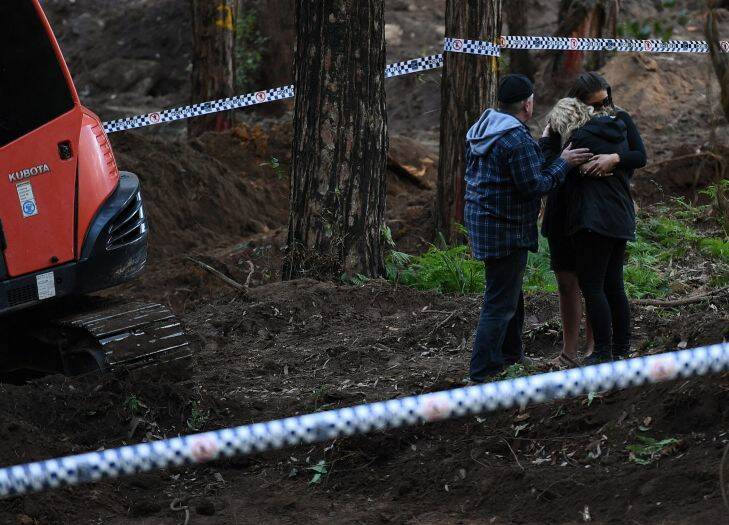 Faye Leveson (centre) is comforted by a family friend and her husband Mark Leveson (left) at the edge of the crime scene where human remains have been unearthed at the possible burial place of Matthew Leveson in the Royal National Park at Waterfall, NSW. 31st May, 2017. Photo: Kate Geraghty
