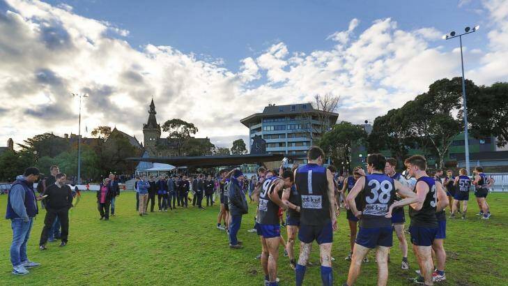 The crowd hovers around the huddle at a University Blues home match at University Oval. Photo: Uni Blues