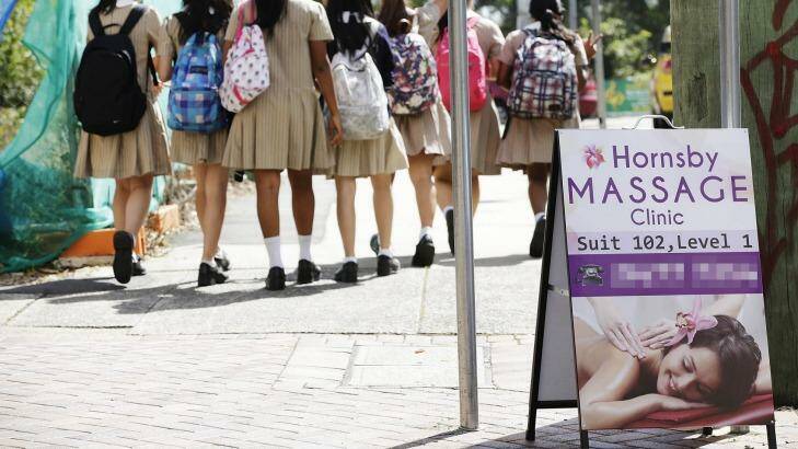 Pupils pass a sign for a massage parlour believed to be operating as an illegal brothel near Hornsby Girls High School. Photo: Jessica Hromas